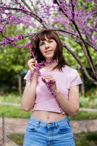 Portrait of a young girl in a flowering tree. A brunette girl on the background of a blooming rosewood.