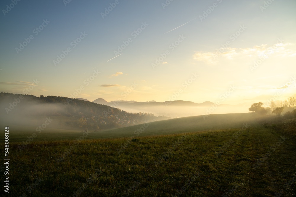 Sunrise and sunset, beautiful clouds over the meadow, hills and buildings in the town. Slovakia