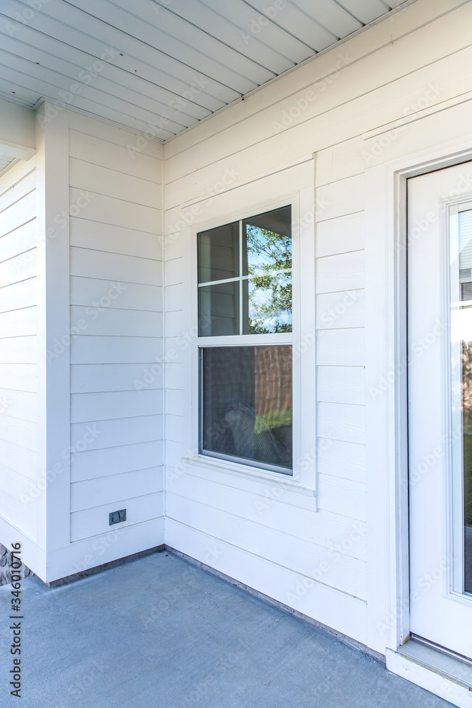Fototapeta premium Zewnętrze domu z białą bocznicą z kącikiem werandy i oknem