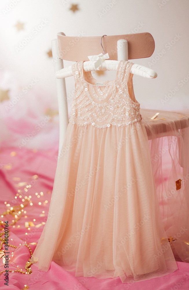 Stock Photo - Child dress on hanger on pink background