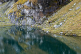 colorful rocky shore mirror reflection in calm Balea mountain lake 