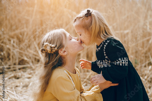 Canvas Print two little blonde sisters on a background of a golden field