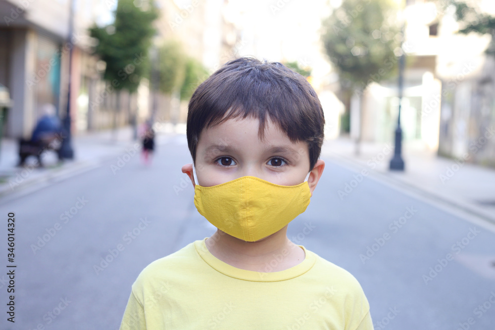 niño en medio de la calle con mascarilla casera de tela debido a la pandemia del coronavirus - obrazy, fototapety, plakaty 