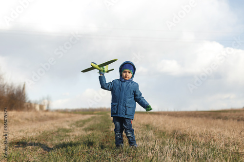 Wallpaper Mural The boy is standing in the dry grass, looking into the camera, dreaming and holding a green airplane. Torontodigital.ca