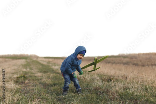 Boy playing with toy glider in field on spring day