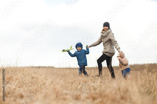Wallpaper Mural Young mother with two children, a little girl and a boy playing in the autumn field. Autumn family in the Park playing with toy airplane. Torontodigital.ca
