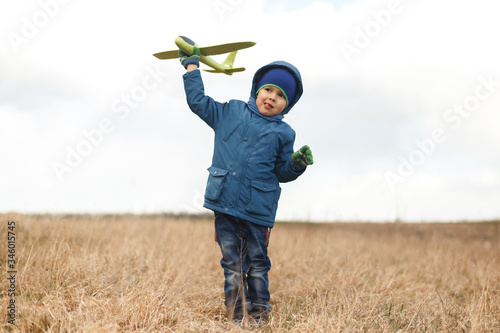 Wallpaper Mural The boy is standing in the dry grass, looking into the camera, dreaming and holding a green airplane. Torontodigital.ca