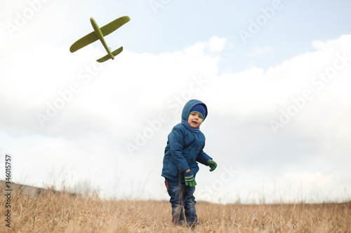 Boy playing with toy glider in field on spring day