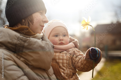 Young mother with her little daughter that hold yellow flower.