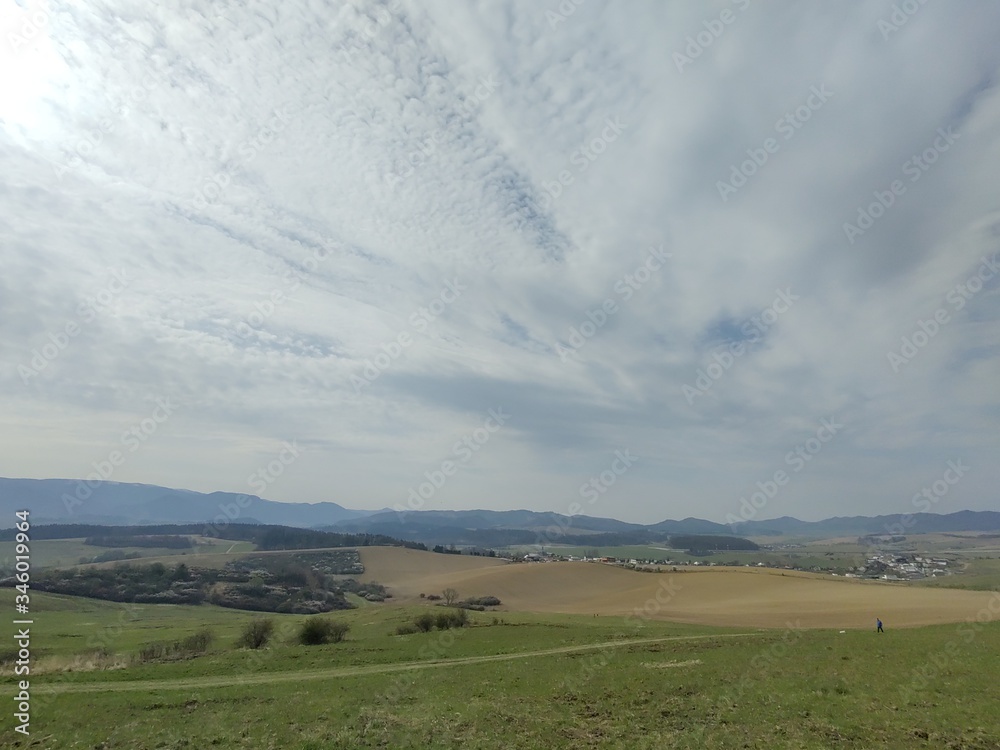 Obraz premium Sunrise and sunset, beautiful clouds over the meadow, hills and buildings in the town. Slovakia