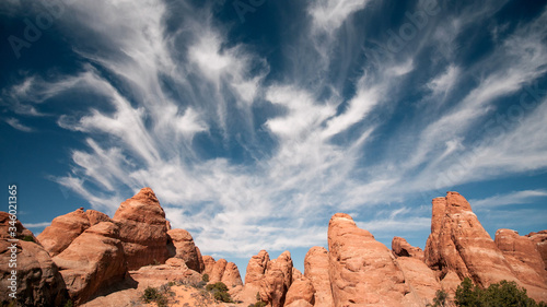 Fotografie Red rock sandstone fins in the Utah Desert, as clouds move through the sky in time lapse at Arches National Park