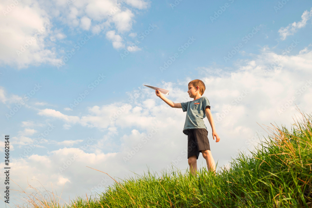 Little boy launches a paper plane into the air. Child launches a paper plane. Happy kid playing with paper airplane Little boy launches a paper plane into the air. Child launches a paper plane. Happy kid playing with paper airplane