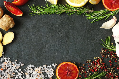 Selective focus. Set spice on a black stone board. Peppers mix, Himalayan salt, rosemary, garlic, lemon, ginger, red orange. Spices for fish or meat. Spices for marinade. Spices for a healthy diet.