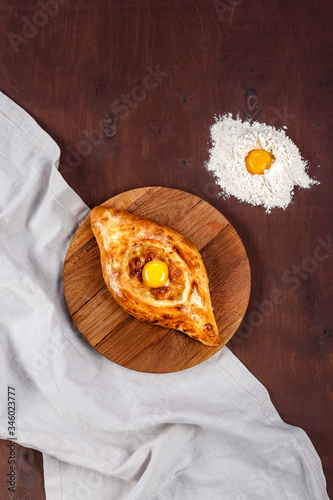 Ajarian hachapuri on wooden table with cotton fabric. Restaurant menu concept. Space for text photo