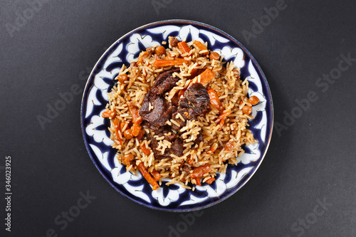 Plov pilaf plate on black background. Traditional Uzbek cuisine.  Top angle