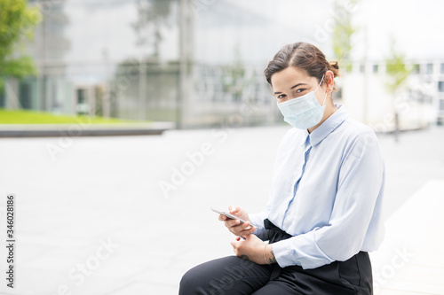 Frau mit Smpartphone macht Pause vor Bürogebäude auf Campus oder Technologiepark.  photo