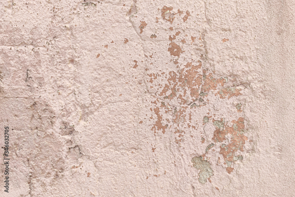 Old, weathered wall background texture. Painted pastel pink, with peeling and cracked paint and plaster.