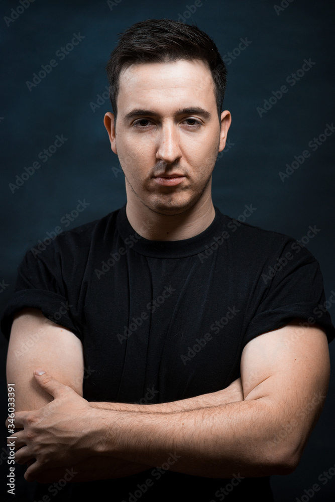 Handsome muscular young man on dark with stern expression