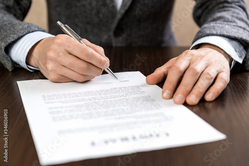 A businessman sits at an office Desk and signs a contract with a ballpoint pen