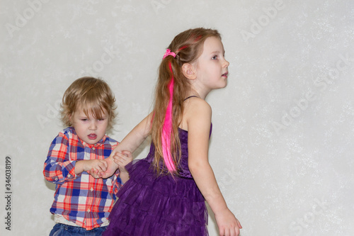 The little brother pulls his distracted sister in his direction. The boy gripped the girls hand and drags it back.