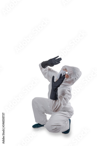 Man wearing protection suit, goggles and mask for fighting Covid-19 (Corona virus) crouched stands cowering under something dangerous above him. Isolated