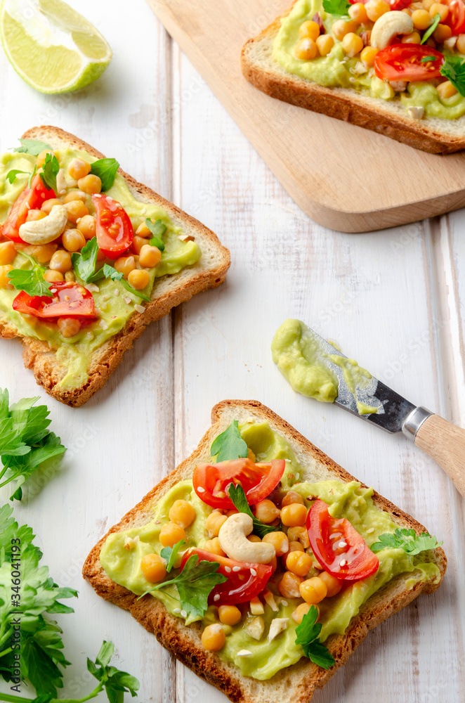Vegan sandwich with avocado, nuts, vegetables and olive oil on white wooden table Vegan sandwich with avocado, nuts, vegetables and olive oil on white wooden table