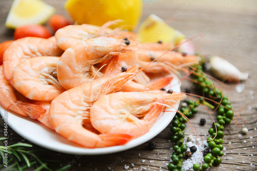 fresh shrimp on white plate with ingredients herb and spices - cooking seafood shrimps prawns served on a wooden table background fresh shrimp on white plate with ingredients herb and spices - cooking seafood shrimps prawns served on a wooden table background