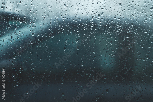 Raindrops on glass. view through the car window. heavy rain. abstract background with drops on transparent surface © maxkolmeto
