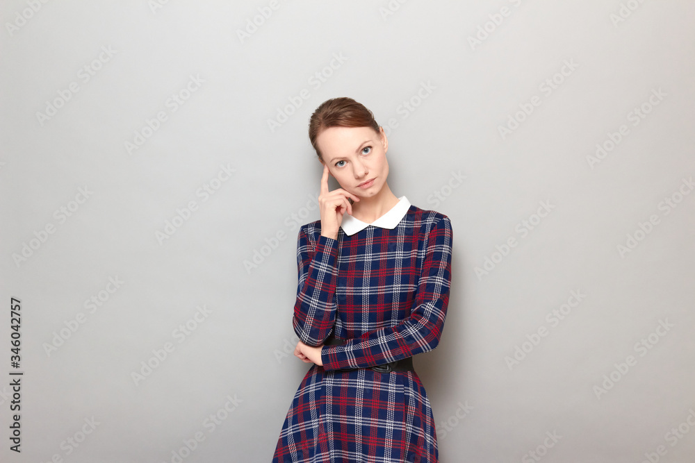 Portrait of serious focused young woman touching temple with finger Portrait of serious focused young woman touching temple with finger