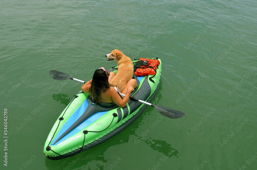 Overhead view of a young woman and her pet dog in a one place inflatable kayak.