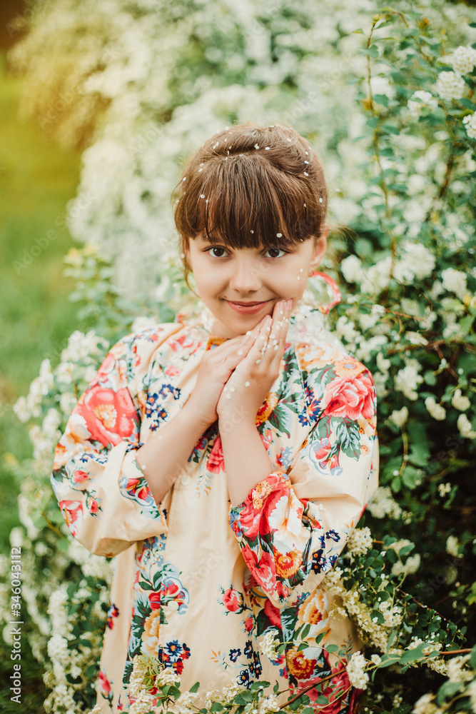 Beautiful girl in a bright raincoat walks after the rain in the park. Excellent spirea flowering bushes. Soft focus. Happy childhood concept Beautiful girl in a bright raincoat walks after the rain in the park. Excellent spirea flowering bushes. Soft focus. Happy childhood concept
