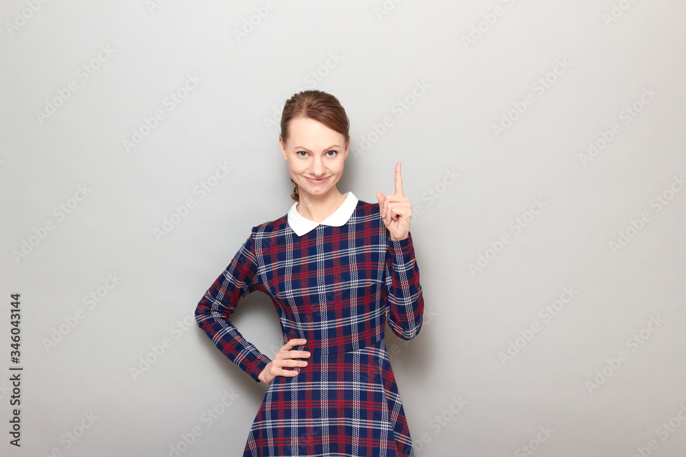 Portrait of happy young woman smiling and pointing up with finger Portrait of happy young woman smiling and pointing up with finger