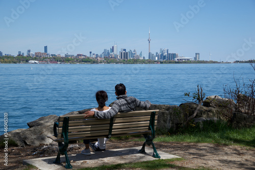 Photography couple sitting on the park bench with Toronto as background