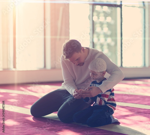 father and son in mosque praying and reading holly book quran together