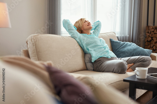 Mature Woman. Beautiful Healthy Middle Age Female Sitting On Sofa At Home. Beauty And Comfort Concept.