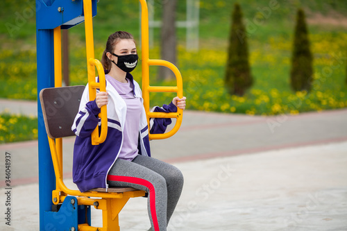 COVID-19. Young caucasian teenage girl in a black mask goes in for sports on a street sports ground during a pandemic. Coronavirus in Europe.