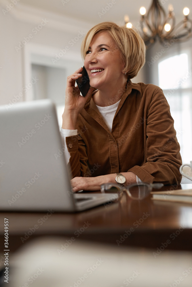 Businesswoman Homework. Female With Laptop. Mature Woman In Brown Jacket And Eyeglasses Talks On Phone. Businesswoman Homework. Female With Laptop. Mature Woman In Brown Jacket And Eyeglasses Talks On Phone.