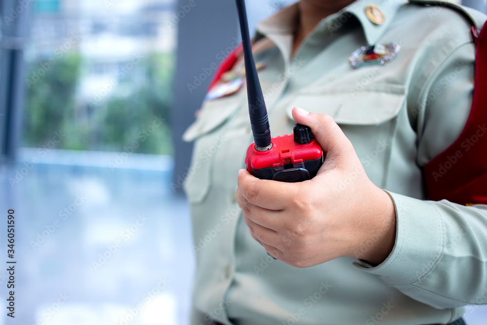 Security guard uses radio communication for facilitate traffic. Security officers use walkie talkie to maintain order in office building in Thailand.