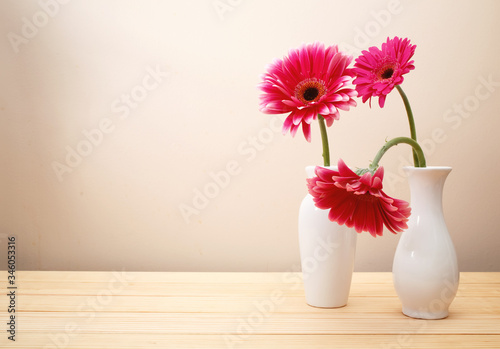 Gerbera flowers in a white vase on a wood table