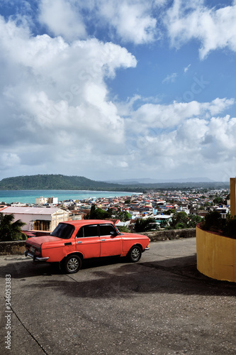 Baracoa, Cuba - aerial view of the town and the sea with a classic car in foreground