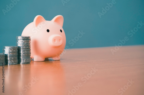 pink piggy bank and money stack tower on a wooden office desk table