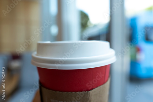 Blurred Red paper coffee cup with White plastic lid in bokeh blurred background, Close up & Macro shot, Selective focus, About drink concept