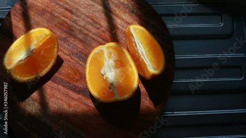 one slice of orange fruit picked by asian human hand from wooden chopping board.