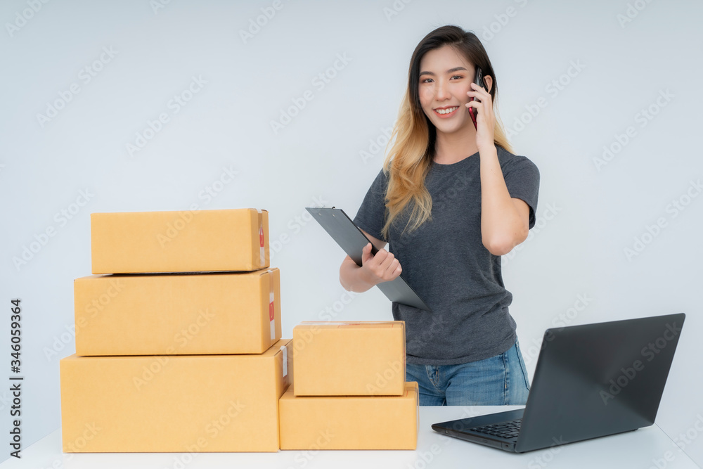 Asia woman freelancer working and checklist and writing order with cardboard box on bed at home Asia woman freelancer working and checklist and writing order with cardboard box on bed at home