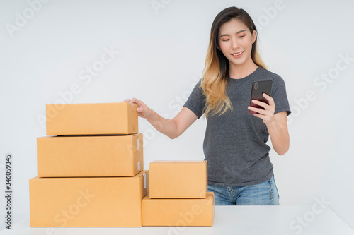 Asia woman freelancer working and checklist and writing order with cardboard box on bed at home 
