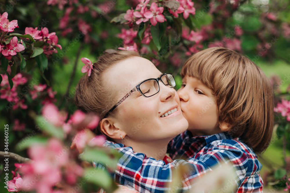 Mother and baby in blooming garden. Mom and child in spring. Springtime family scene. Flowers of apple or cherry tree. Mother and baby in blooming garden. Mom and child in spring. Springtime family scene. Flowers of apple or cherry tree.