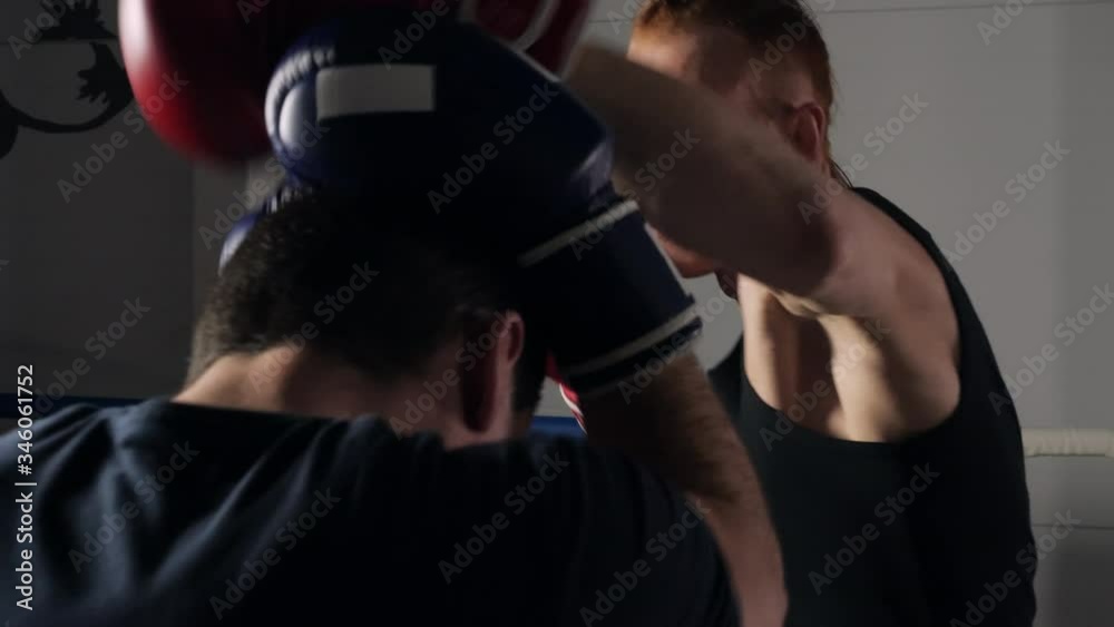 Boxer man in gloves fighting with sparring partner on boxing training. Figter man training Muay Thai in fighting club. Two kickboxer fighting in training ring Boxer man in gloves fighting with sparring partner on boxing training. Figter man training Muay Thai in fighting club. Two kickboxer fighting in training ring