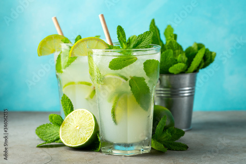 Two homemade lemonade or mojito cocktail with lime, mint and ice cubes in a glass on a light stone table. Fresh summer drink.