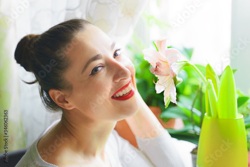 Close up indoor photo of beautiful young woman surrounded by flowers. Spring blossom.Portrait happy smiling girl over spring flowers background