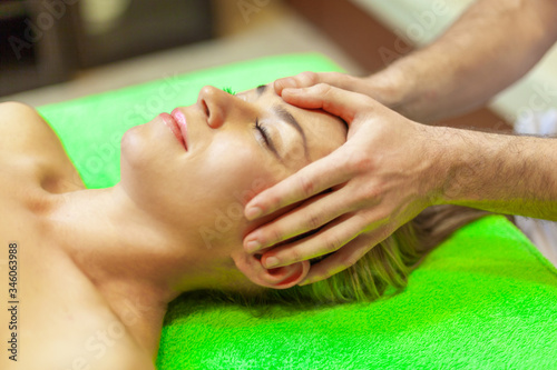 Close up of beautiful young woman relaxing with face massage at beauty spa